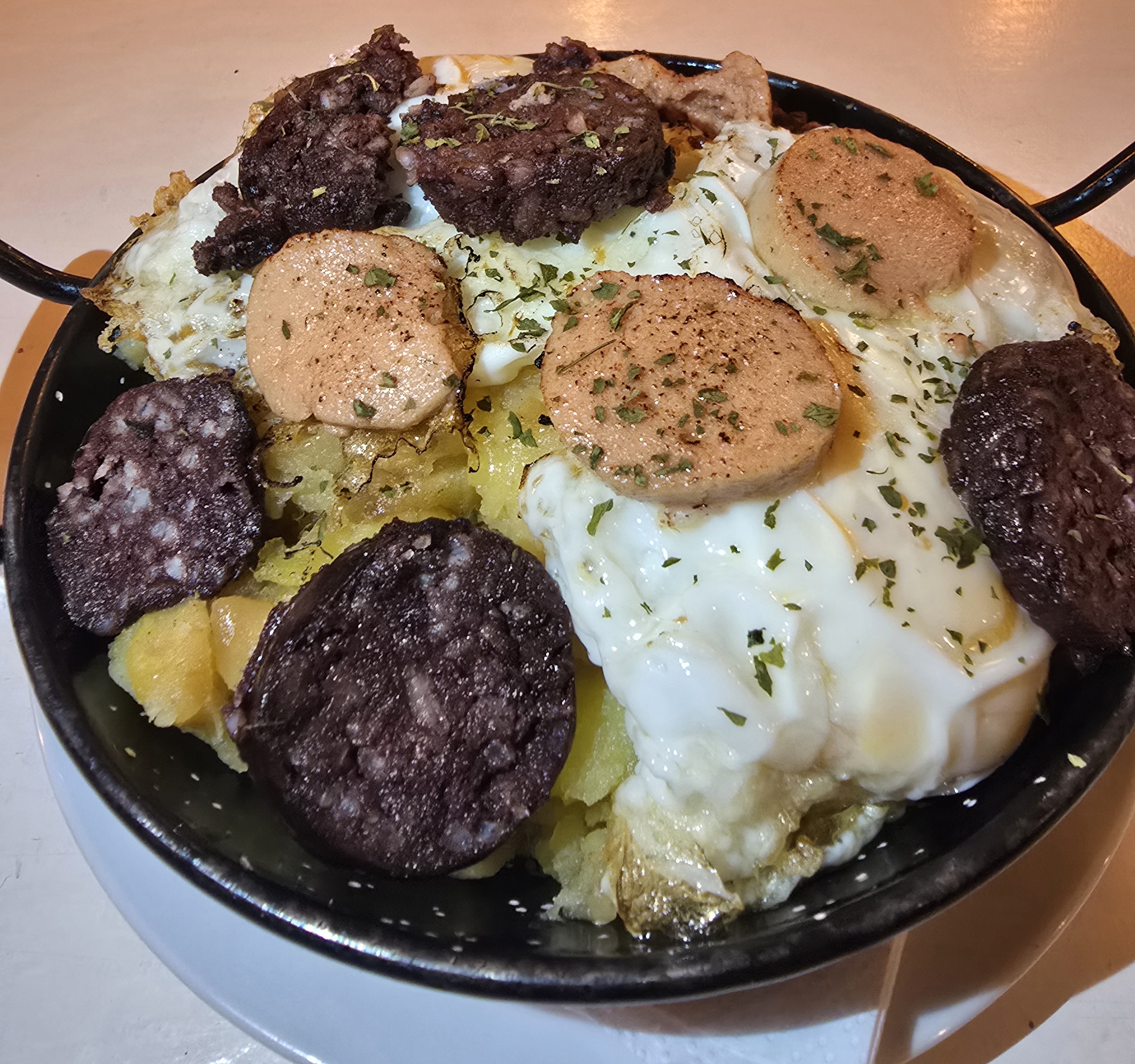 Potatoes and onion, fried eggs with grilled blood sausage and foie gras