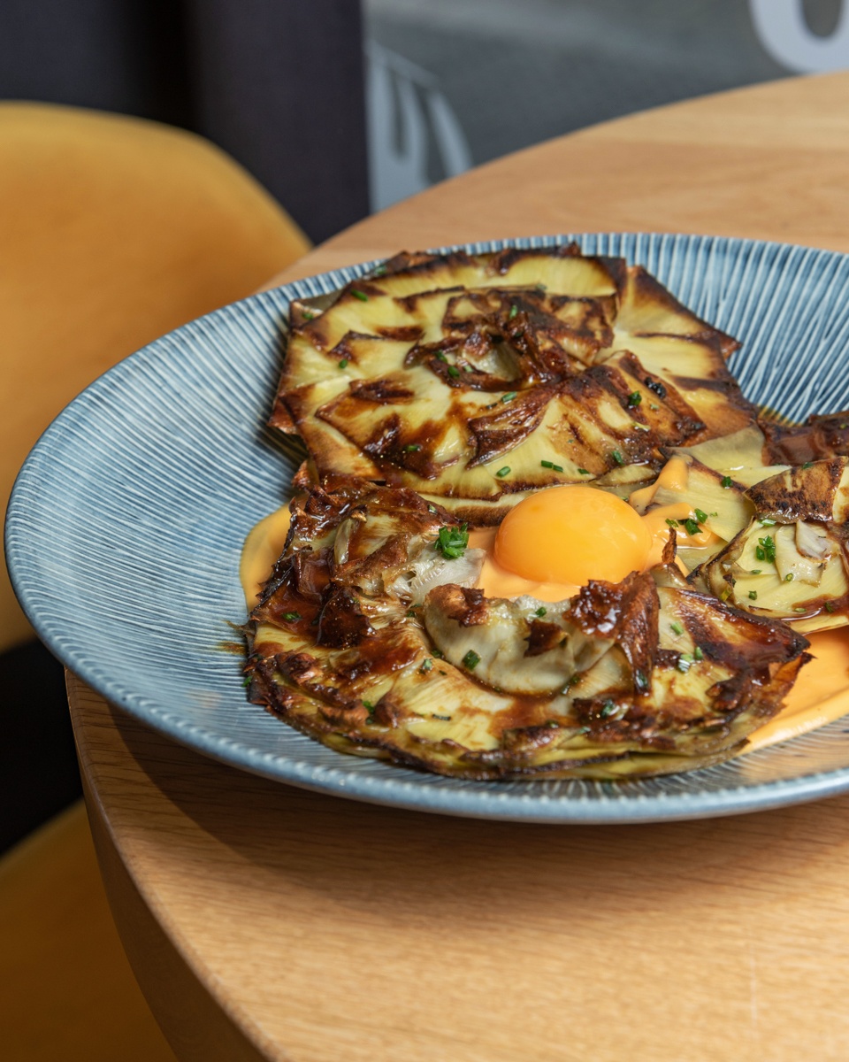 Alcachofas confitadas a las plancha, crema de boniato revolcón y yema de huevo campero