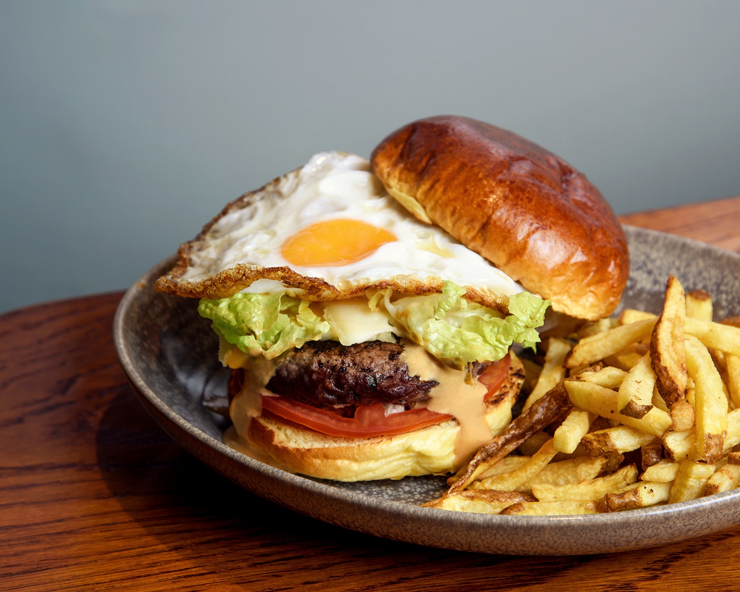 Hamburguesa especial de ternera premium con queso arzúa, salsa rosa ahumada, tomate, lechuga y patatas fritas servida en pan brioche. 