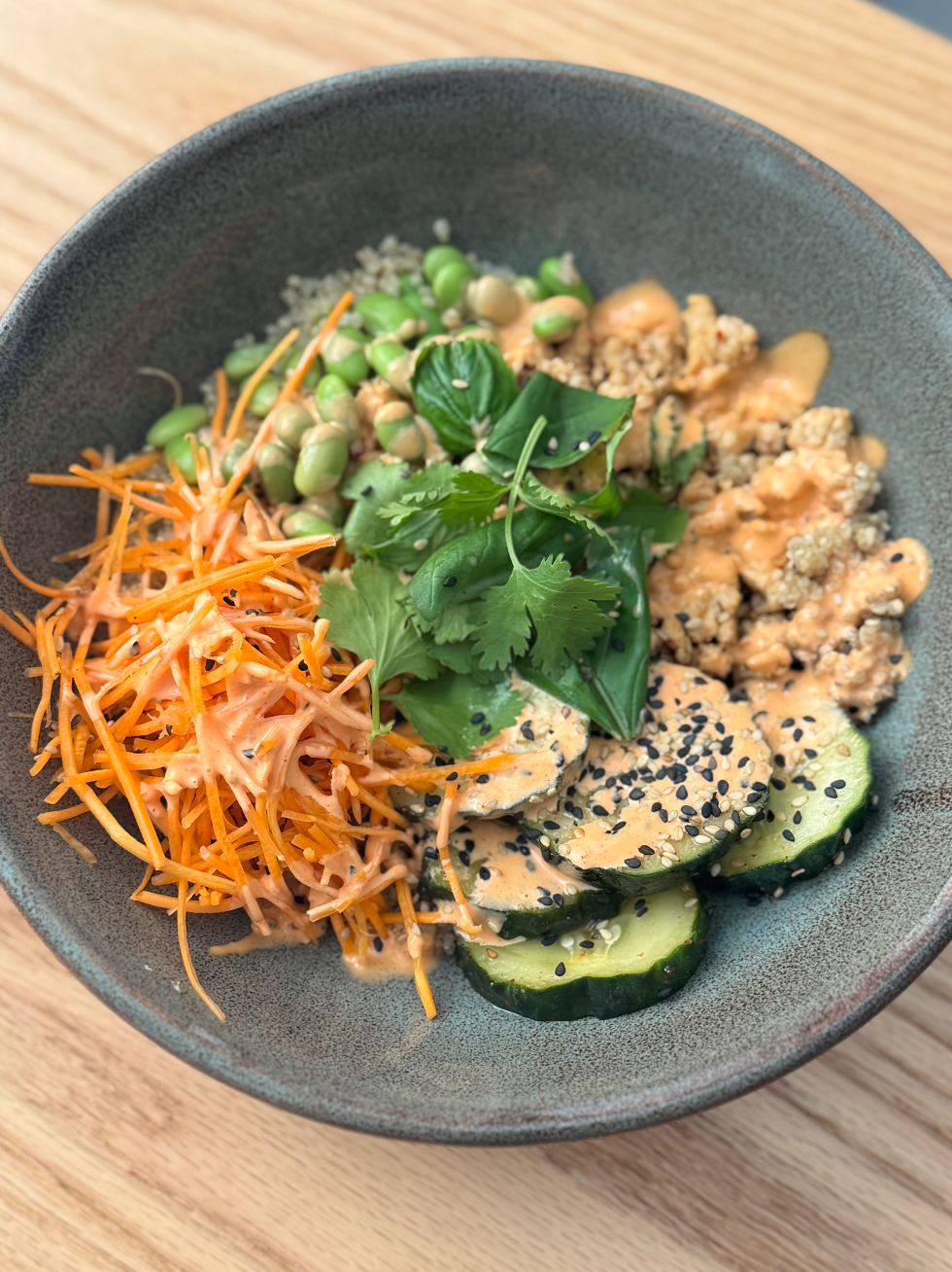 BANH MI BOWL: base de quinoa con pepino encurtido, zanahorias, edamame, pollo marinado y hierbas. Servido con salsa picante.