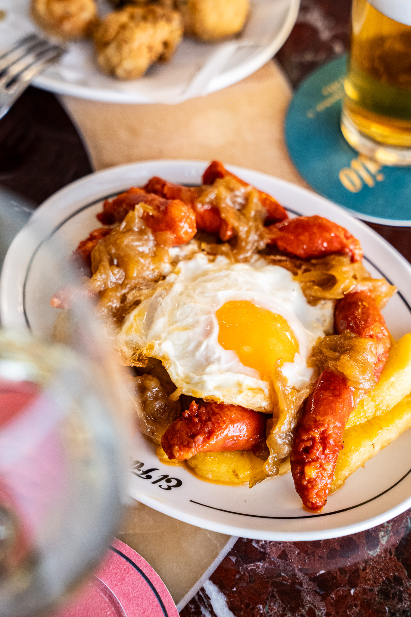 Huevos rotos con chistorra, cebolla caramelizada y patatas