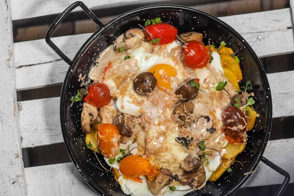 Huevos rotos con patatas, crema de portobello y virutas de foie