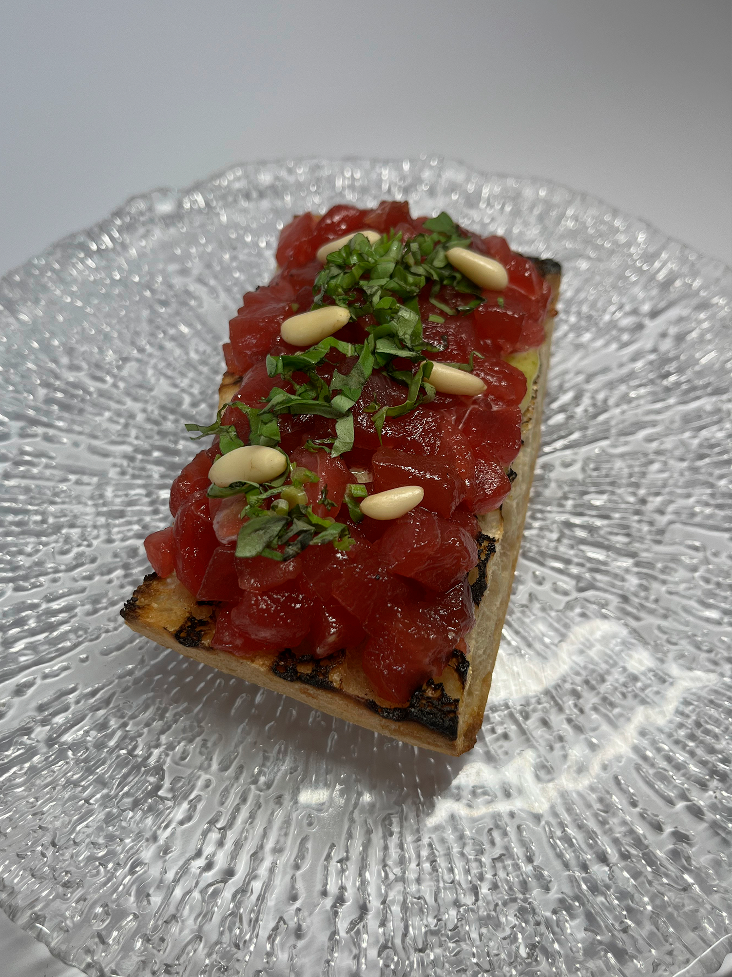 Toast on glass bread with marinated tuna, pistachio, pine nuts and basil