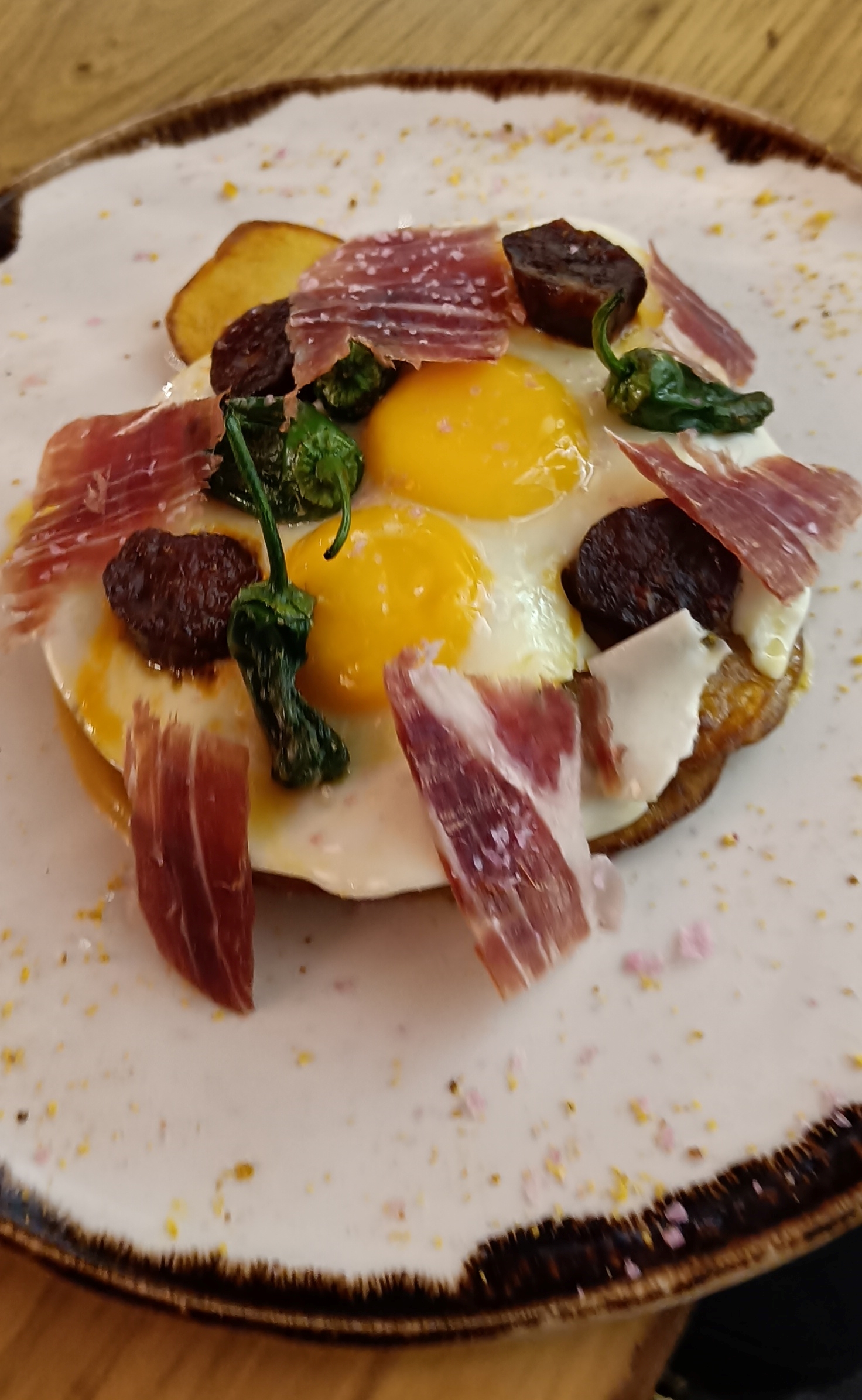 Huevos rotos trufados con patatas, tomate casero, jabuguitos y jamón ibérico