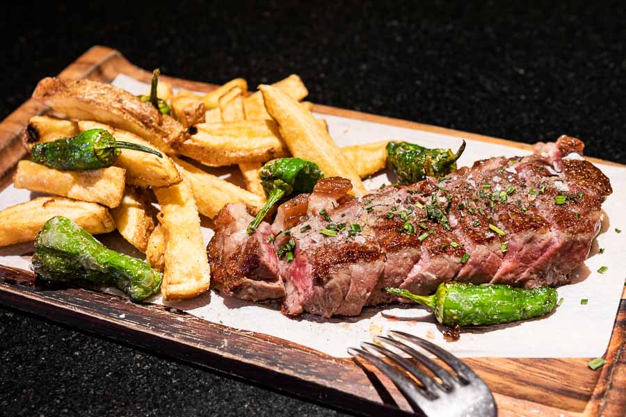 Grilled prime beef entrecotte, sliced, over frie