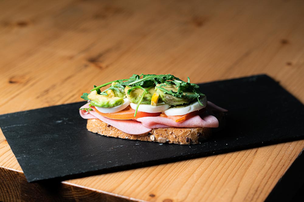 Tostada con jamón dulce, rúcula, tomate, queso en lonchas duro sobre pan rustico
