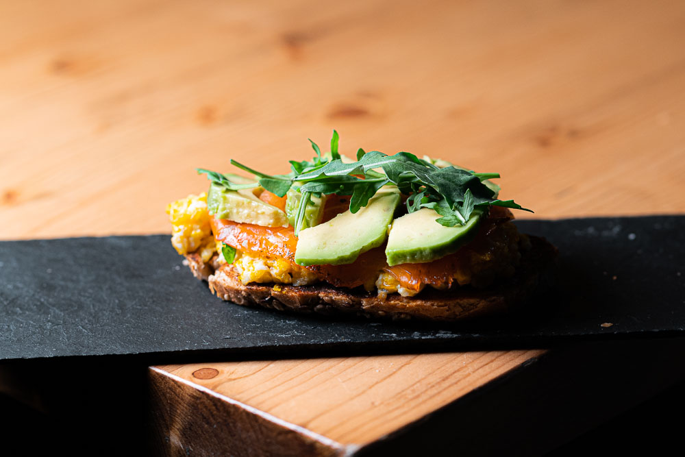 Tostada de salmón con huevo revuelto, rúcula y aguacate.