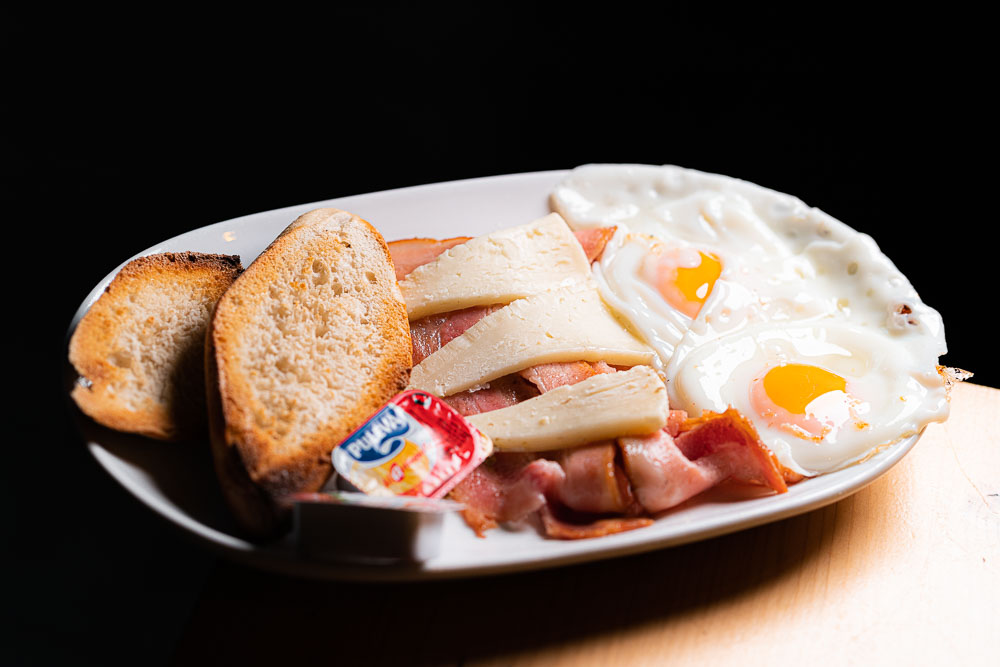 Un par de huevos fritos o revueltos con bacon, queso, tostada, zumo natural y café.